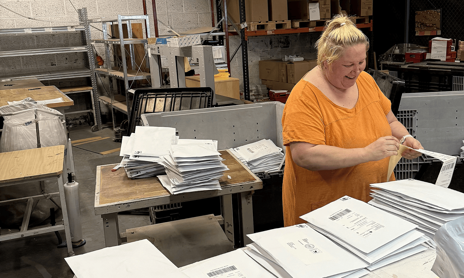 Manuell pakking utført av smilende kvinnelig kollega i Aksell logistikk